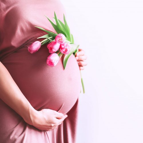 Beautiful,Pregnant,Woman,With,Tulips,Flowers,Holds,Hands,On,Belly